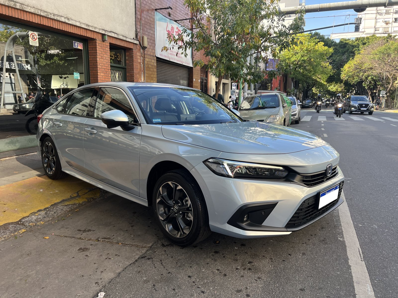 Honda Civic 2025, gris plata, en la puerta del local